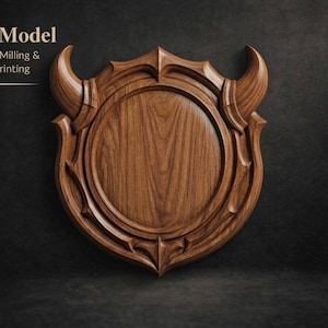 May include: A detailed wooden shield-shaped carving with a central circular design and decorative horns. The text "3D Model For CNC Milling & D Printing" is displayed at the top. The wood grain is visible, and the piece is set against a dark background.