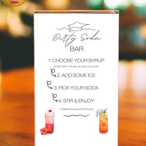 May include: A clear acrylic sign with the words "Dirty Soda Bar" in elegant script. The sign details the steps to create a soda, including choosing syrup, adding ice, picking soda, and stirring. Two colorful soda illustrations are shown.