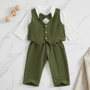 May include: A long-sleeve white shirt paired with an olive green vest and matching trousers. The vest features a pointed collar, a matching olive green bow tie, and four light-colored buttons down the front. The outfit is presented as a set.