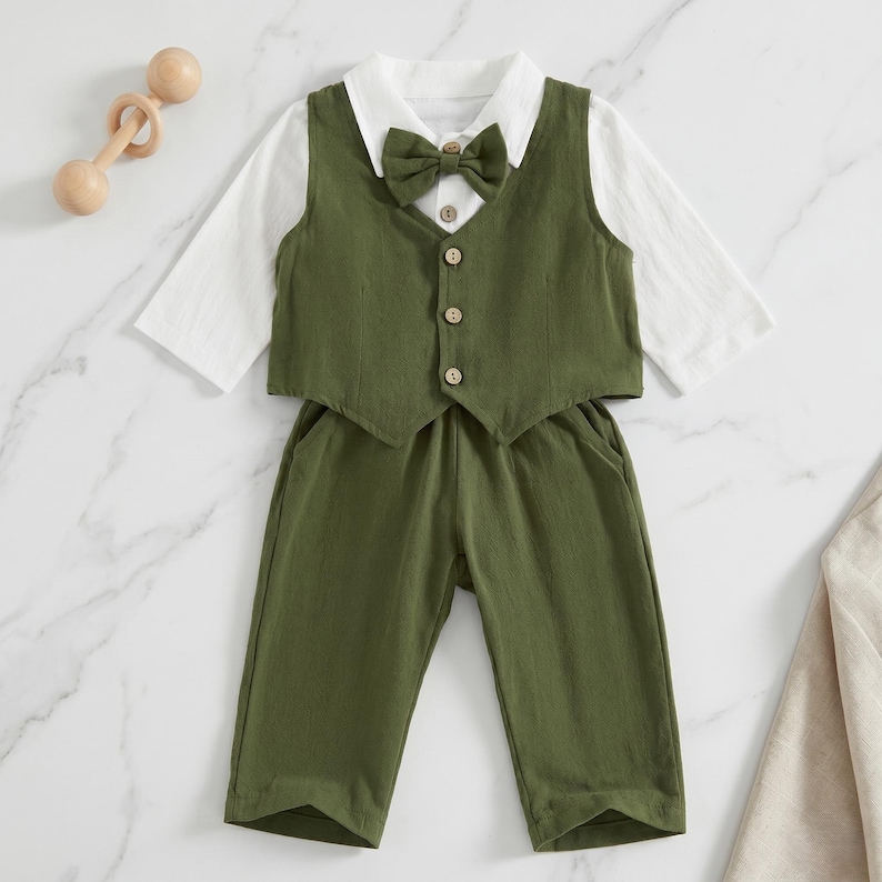 May include: A long-sleeve white shirt paired with an olive green vest and matching trousers. The vest features a pointed collar, a matching olive green bow tie, and four light-colored buttons down the front. The outfit is presented as a set.