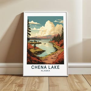 May include: A framed art print featuring a scenic view of Chena Lake in Alaska. The artwork depicts a serene lake surrounded by lush green trees, red and brown foliage, and distant mountains under a blue sky with fluffy white clouds. The text "CHENA LAKE ALASKA" is printed at the bottom.