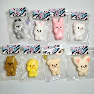 Puede incluir: Una colección de juguetes con forma de animales de estilo caricatura en envases de plástico transparente. Los juguetes incluyen un lobo gris, un conejo blanco, un conejito rosa, un oso blanco, un oso marrón, un pollito amarillo, un perro beige y un conejo color crema.