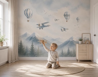Puede incluir: Un mural de pared con un paisaje en acuarela de montañas nevadas y un bosque de pinos. El cielo está lleno de globos aerostáticos azules y blancos y aviones antiguos. El diseño utiliza tonos suaves y apagados para crear un ambiente sereno.