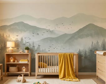 Puede incluir: Una habitación infantil con un gran mural de pared de montañas verdes brumosas y un bosque con una bandada de pájaros en vuelo. La habitación incluye una cuna de madera con una manta amarilla mostaza, una estantería y un cambiador de madera.