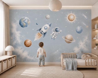 Puede incluir: Un mural de pared que presenta una escena espacial en acuarela con un cohete, un astronauta, varios planetas, estrellas y cometas sobre un fondo azul claro. El diseño incluye una gran Tierra, un sol, Saturno y otros cuerpos celestes.