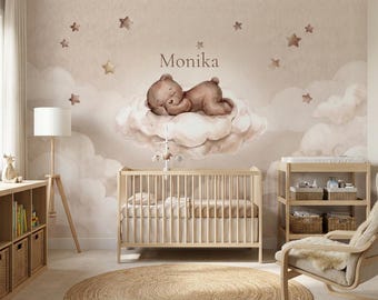 Puede incluir: Un mural de pared que presenta un oso pardo durmiendo sobre una nube grande y esponjosa rodeada de estrellas dispersas. El nombre Monika está impreso en letras de color marrón oscuro sobre el oso. El diseño utiliza tonos de acuarela beige.