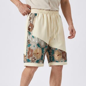 Peut inclure: Shorts crème avec un motif floral. Ces shorts présentent une taille élastique avec cordon de serrage et un design unique avec des broderies florales dans les tons de marron, vert et crème. Les shorts arrivent au niveau du genou.
