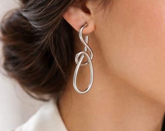 Moderne zilveren knoop oorbellen, abstract lusstatement, minimalistische lange sieraden