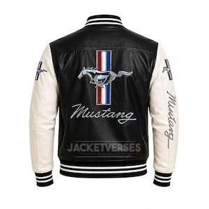 Op de afbeelding: Zwart en witte leren jas met crèmekleurige mouwen. De achterkant heeft een Mustang-logo met een rennend paard, rood-wit-blauwe strepen en het woord "Mustang" in cursief. De jas heeft een gestreepte kraag en manchetten.