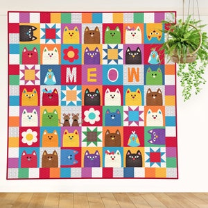 The Catnip Cats quilt pattern. This is a gorgeous quilt made up of appliqued cats, mice, birds, and flowers. It is laid out with Sawtooth Star blocks and has a simple square block border. The quilt is displayed against a white wall.