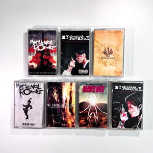 May include: Seven cassette tapes featuring album art from My Chemical Romance. The tapes showcase diverse album covers with text and graphics, including "The Black Parade" and "Danger Days". The tapes are in clear plastic cases.