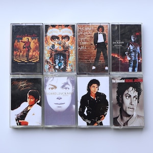 May include: Collection of eight vintage cassette tapes featuring Michael Jackson album covers. The tapes showcase various album art, including "Thriller," "Off the Wall," and "Dangerous," with images of the artist in different poses and styles.