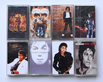 May include: Collection of eight vintage cassette tapes featuring Michael Jackson album covers. The tapes showcase various album art, including "Thriller," "Off the Wall," and "Dangerous," with images of the artist in different poses and styles.