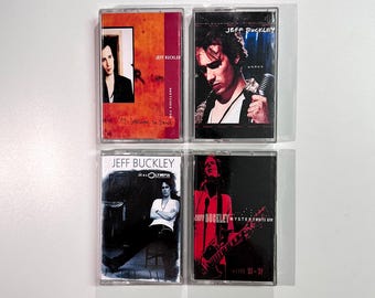 May include: Four cassette tapes featuring Jeff Buckley album art. The tapes have various color schemes, including orange, blue, and red. Each tape displays the artist's name and album titles, with images of Buckley.