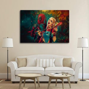 K&ouml;nnte beinhalten: Leinwanddruck mit Deadpool und Harley Quinn. Deadpool tr&auml;gt seinen rot-schwarzen Anzug, und Harley Quinn ihr rot-wei&szlig;-blaues Outfit, mit einer Spielzeugpistole. Der Hintergrund hat ein farbenfrohes, abstraktes Design.