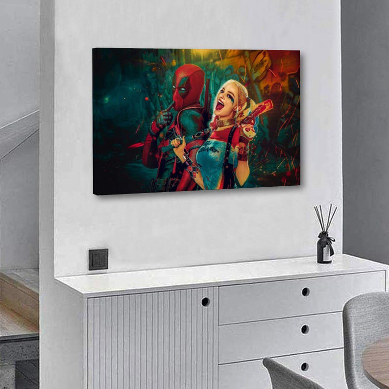 K&ouml;nnte beinhalten: Ein rechteckiger Leinwanddruck mit Deadpool und Harley Quinn. Deadpool tr&auml;gt seinen rot-schwarzen Anzug, und Harley Quinn ist in ihrem typischen Outfit zu sehen, mit einer Spielzeugpistole. Der Hintergrund hat ein dunkles, farbenfrohes und abstraktes Design.
