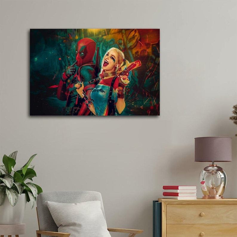 K&ouml;nnte beinhalten: Leinwanddruck mit Deadpool und Harley Quinn. Deadpool tr&auml;gt seinen rot-schwarzen Anzug, und Harley Quinn ist in ihrem typischen Outfit zu sehen, mit einem roten Schl&auml;gel. Der Hintergrund hat ein farbenfrohes, abstraktes Design.