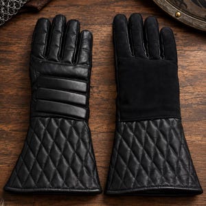 Peut inclure: Une paire de gants en cuir noir avec des manchettes évasées à motif losange matelassé. Le gant gauche présente des bandes horizontales rembourrées sur le dos de la main, tandis que le gant droit possède un empiècement en daim lisse.