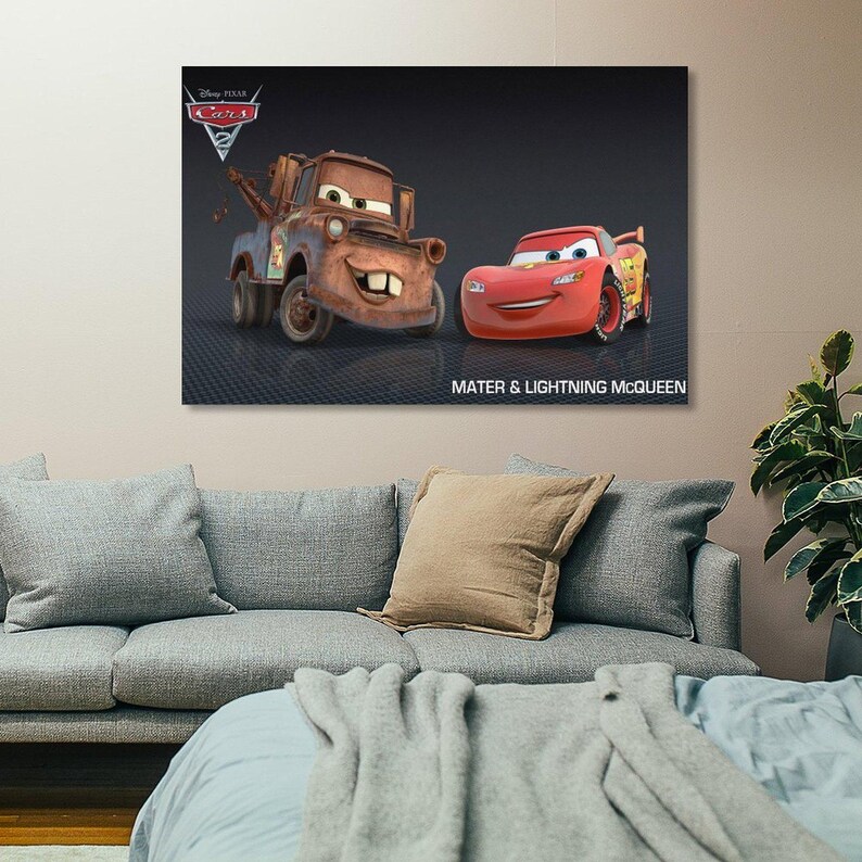May include: A framed canvas print featuring characters from the Disney Pixar Cars 2 movie. The image shows Mater, a brown tow truck, and Lightning McQueen, a red race car, with the text "Mater & Lightning McQueen". The Disney Pixar Cars 2 logo is in the upper left corner.