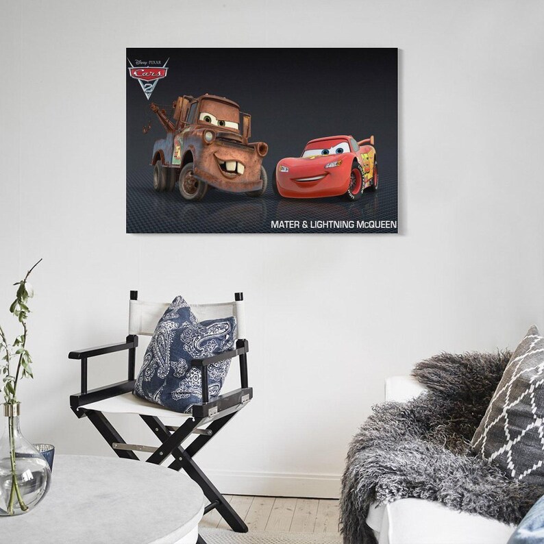 May include: A framed canvas print featuring the Disney Pixar Cars 2 characters Mater and Lightning McQueen. The print shows the two animated cars against a dark background, with the text "Mater & Lightning McQueen" below. The Disney Pixar Cars logo is in the upper left corner.