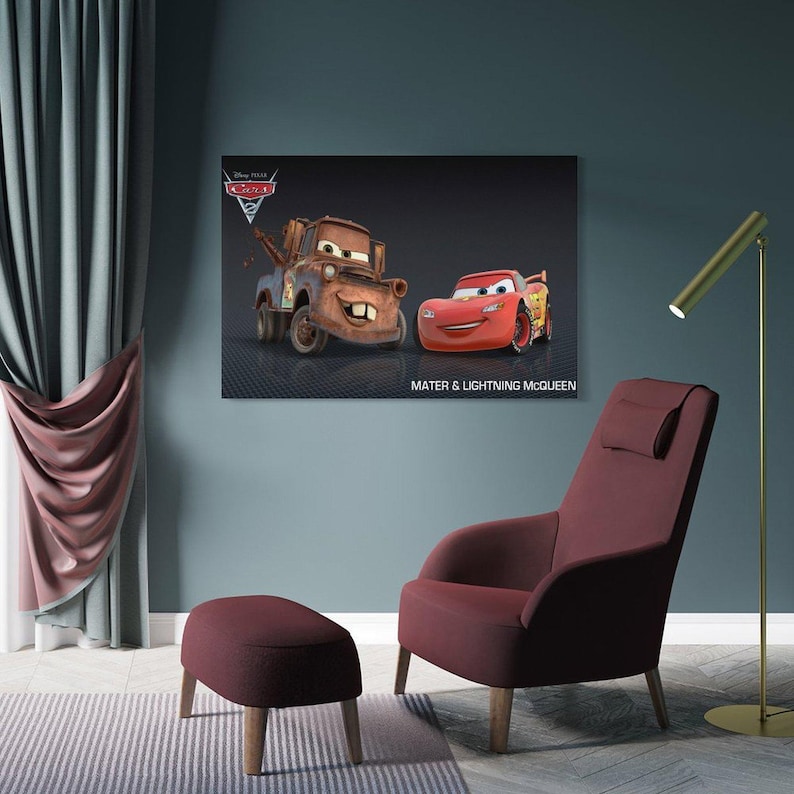 May include: A framed canvas print featuring the animated characters Mater and Lightning McQueen from the Disney Pixar movie Cars. The print is displayed above a burgundy armchair and ottoman. The text "Mater & Lightning McQueen" is below the image.