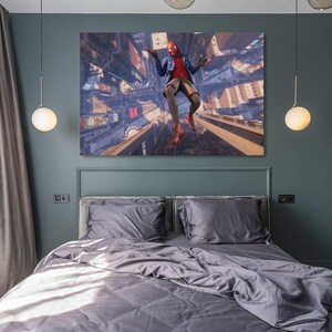 Puede incluir: Un lienzo de un superh&eacute;roe con un traje rojo y negro, en el aire sobre un paisaje urbano. La obra de arte se exhibe sobre una cama con ropa de cama gris, contra una pared verde oscuro. La habitaci&oacute;n est&aacute; iluminada por dos l&aacute;mparas colgantes.