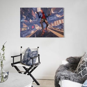 Puede incluir: Impresi&oacute;n en lienzo enmarcada que representa a un superh&eacute;roe con una m&aacute;scara roja y negra, camisa roja, chaqueta azul y pantalones cortos color canela, en el aire sobre un paisaje urbano. La obra de arte se exhibe en una pared blanca sobre una silla de director en blanco y negro.