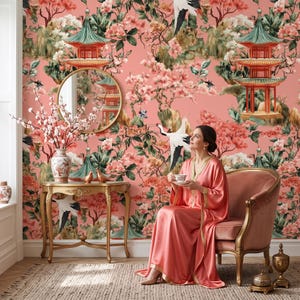 May include: Wallpaper featuring a coral pink background with a repeating pattern of green and red pagodas, blooming cherry blossom branches, and white cranes. The design includes detailed foliage and floral elements in shades of pink and green.