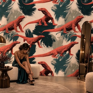 May include: Wallpaper featuring a repeating pattern of bright orange Komodo dragons set against a backdrop of abstract, dark teal and grey brushstrokes on a light cream surface, creating a bold and textured visual effect for interior walls.