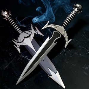 May include: Two crossed daggers with silver-toned blades and black-and-silver ribbed handles. The daggers feature pointed crossguards and spherical pommels. The blades have a central black stripe running down the length, tapering to a sharp point.