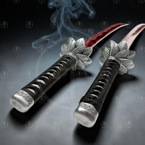 May include: Two swords with curved blades featuring a red pattern. The handles are wrapped in black cord and feature a silver-toned metal guard shaped like a lotus flower. The pommel is a silver-toned metal cap with engraved geometric patterns.