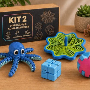 Puede incluir: Una colección de juguetes antiestrés coloridos, que incluyen un pulpo azul, una peonza azul y verde, un cubo azul y una bola rosa y azul. Una caja con el texto "KIT 2" está en el fondo.