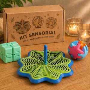 Puede incluir: Un kit sensorial con una caja de cartón marrón, un trompo verde y azul, un cubo verde y una bola de rompecabezas colorida. La caja tiene ilustraciones y el texto "KIT SENSORIAL". Velas y una pequeña planta en el fondo.