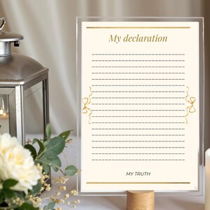 Op de afbeelding: Een helder acrylbord met de tekst "My declaration" en "MY TRUTH" in gouden letters. Het bord heeft een crèmekleurige achtergrond met stippellijnen om op te schrijven en gouden lintaccenten. Het wordt vastgehouden door een houten voet.