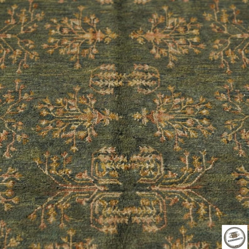 May include: Close-up of a green rug with an intricate floral pattern in shades of gold and brown. The rug has a textured surface and a symmetrical design, creating a classic and elegant look. The rug is suitable for home decor.