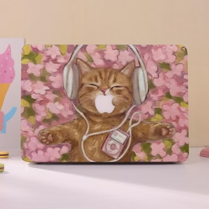 Può includere: Una skin rettangolare per laptop con un'illustrazione in stile pittura a olio di un gatto soriano arancione che indossa cuffie bianche e ascolta un piccolo lettore musicale rosa, su uno sfondo di fiori di ciliegio rosa tenue.