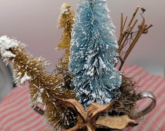 Arreglo floral artificial de invierno en una taza bañada en plata.