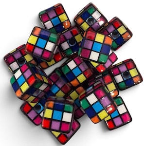 May include: A collection of square-shaped beads, each featuring a grid pattern of nine smaller squares in vibrant colors including red, blue, yellow, green, white, and purple, separated by black lines, with a central hole visible in several beads.