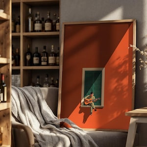 May include: A framed rectangular wall art print featuring a solid burnt orange background with a centered green shuttered window. A small figure sits on the window ledge playing an acoustic guitar, casting a distinct shadow on the orange wall.