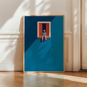 Puede incluir: Una lámina de arte enmarcada que muestra una pared azul intenso con una ventana. Una persona con sombrero, camisa azul y pantalones claros está sentada en el alféizar de la ventana entre contraventanas rojas abiertas bajo sombras marcadas.