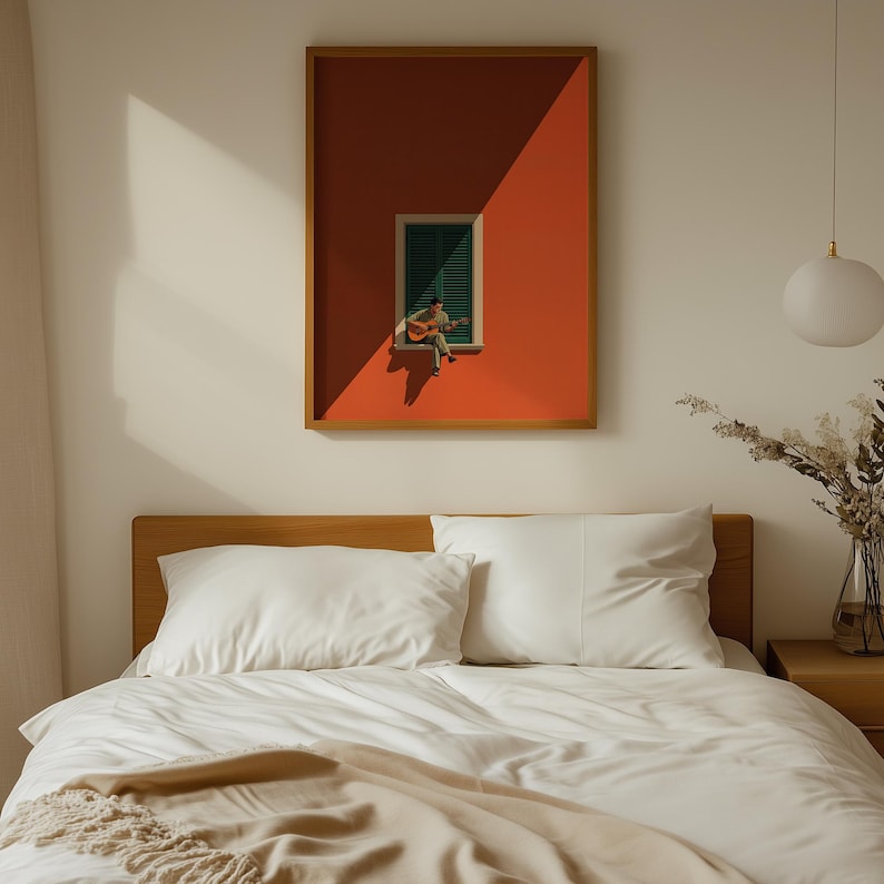 May include: A framed wall art print featuring a vibrant orange wall with a single green shuttered window. A small figure sits on the window ledge playing an acoustic guitar, cast in sharp sunlight and shadow, creating a high-contrast composition.