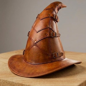 Pode incluir: Um chapéu pontiagudo de couro castanho com uma copa alta e estruturada composta por vários painéis sobrepostos. O chapéu é adornado com várias tiras finas de couro, cada uma fixada com uma pequena fivela de metal e rebites.
