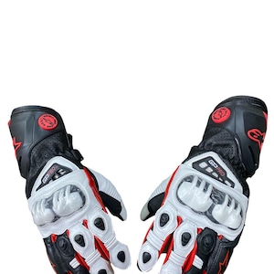 Könnte beinhalten: Paar schwarze, weiße und rote Motorradhandschuhe. Die Handschuhe haben ein perforiertes Design auf dem Handrücken und verfügen über weiße Knöchelschützer. Auf den Handschuhen steht "GP PRO".