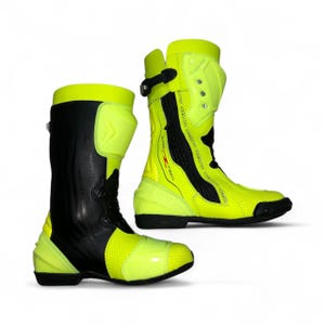 Puede incluir: Par de botas de moto altas en amarillo neón y negro. Las botas presentan un diseño perforado en la puntera y los laterales, con paneles reforzados y cierre de hebilla. Las botas tienen un diseño elegante y moderno.