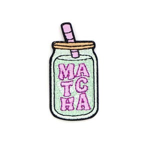 May include: Embroidered patch featuring a matcha drink in a jar with a straw. The jar is light green with the word "MATCHA" in pink, outlined in purple. The patch has a black border and a light brown lid.