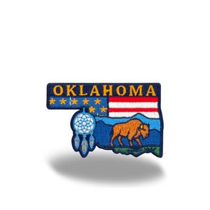 May include: Embroidered patch in the shape of Oklahoma, featuring the state name in gold letters. The design includes a bison, a dreamcatcher, and the state flag. The patch is primarily navy blue, with red, white, and gold accents.