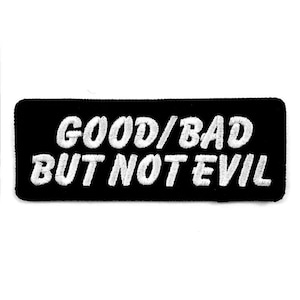 May include: A black rectangular patch with white embroidered text that reads "GOOD/BAD BUT NOT EVIL". The patch has a simple, bold design, suitable for application on clothing or accessories. The text is in a sans-serif font.