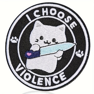 May include: Embroidered patch featuring a white cat holding a light blue knife. The patch is circular with a black background and white text that reads "I CHOOSE VIOLENCE". Includes paw print designs.