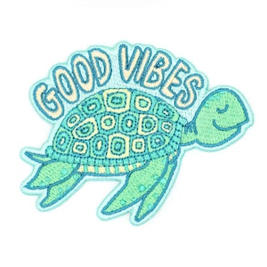 May include: A white ceramic mug with a black handle and the text "But First, Coffee" in a black, handwritten-style font. The mug is on a white surface.