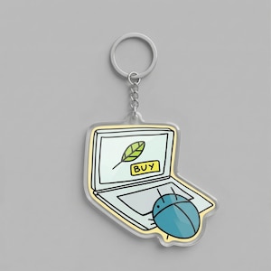 May include: A clear acrylic keychain featuring a cartoon laptop design with a leaf icon and the word "BUY". A blue bug-like character is next to the laptop. The keychain has a silver ring.